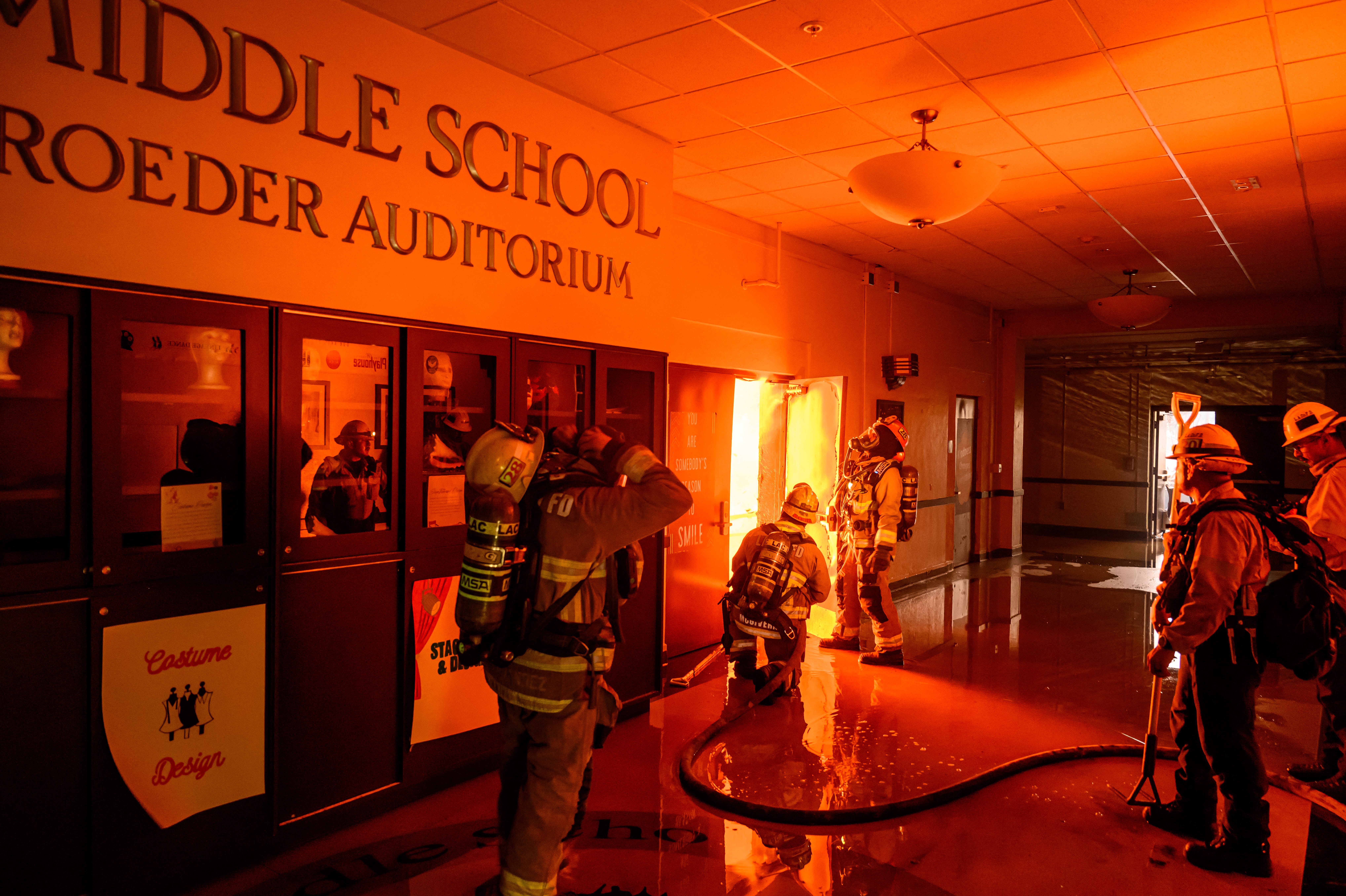 Firefighters prepare to fight flames from inside Eliot Arts Magnet Middle School auditorium as the school burns during the Eaton fire in the Altadena area of Los Angeles County, CA, on Jan. 8, 2025. At least five people are now known to have died in wildfires raging around Los Angeles, with more deaths feared, law enforcement said on Jan. 8, as terrifying blazes leveled whole streets, torching cars and houses in minutes.