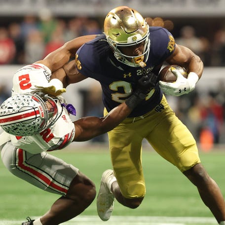 Notre Dame running back Jadarian Price (24) tries to avoid the tackle of Ohio State safety Caleb Downs (2) during the first half the College Football Playoff national championship game at Mercedes-Benz Stadium.