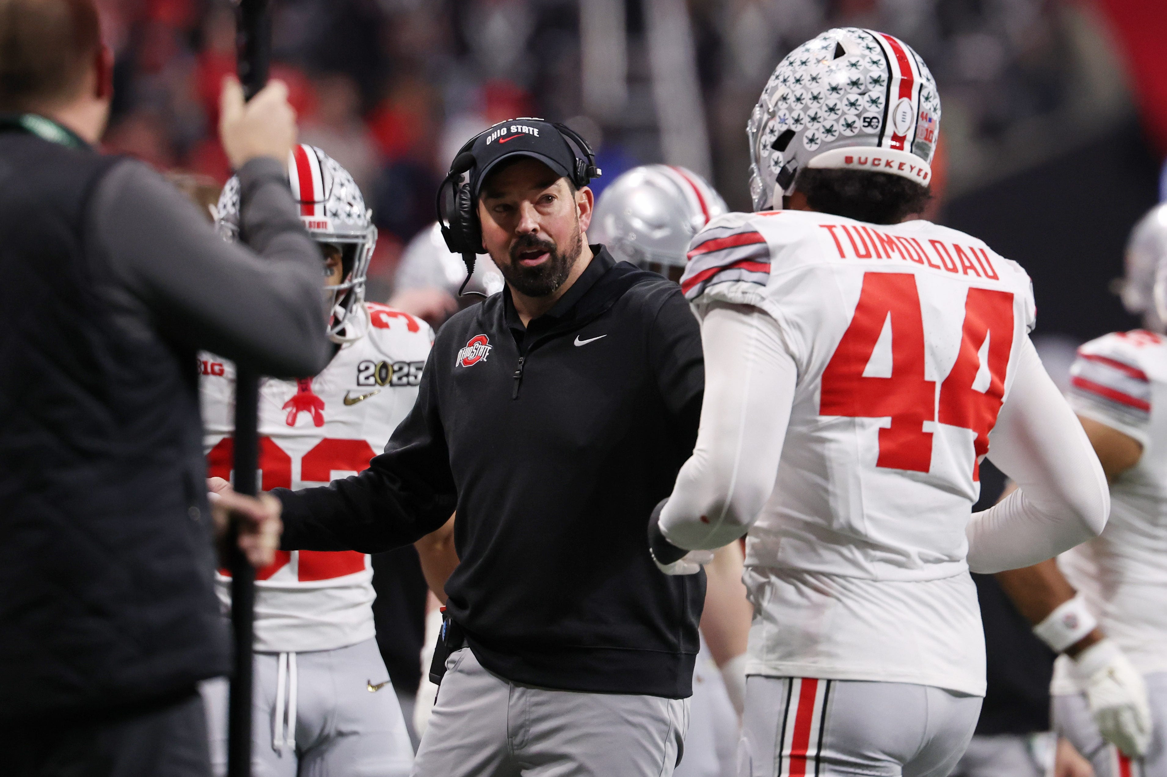 Ohio State coach Ryan Day talks with defensive end JT Tuimoloau (44) during the first half the College Football Playoff championship game at Mercedes-Benz Stadium.