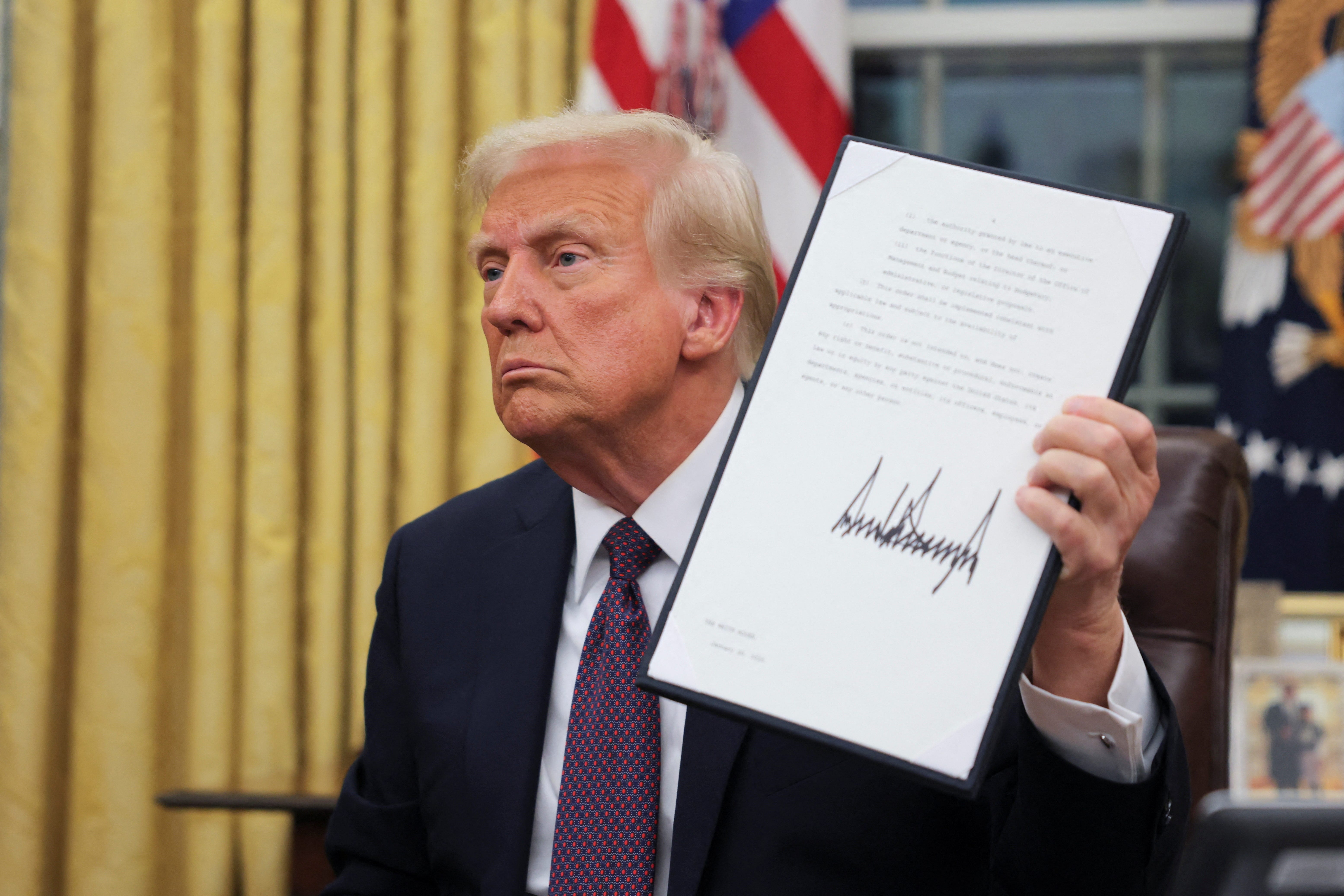 President Donald Trump holds a document he signed in the Oval Office on Jan. 20, 2025.