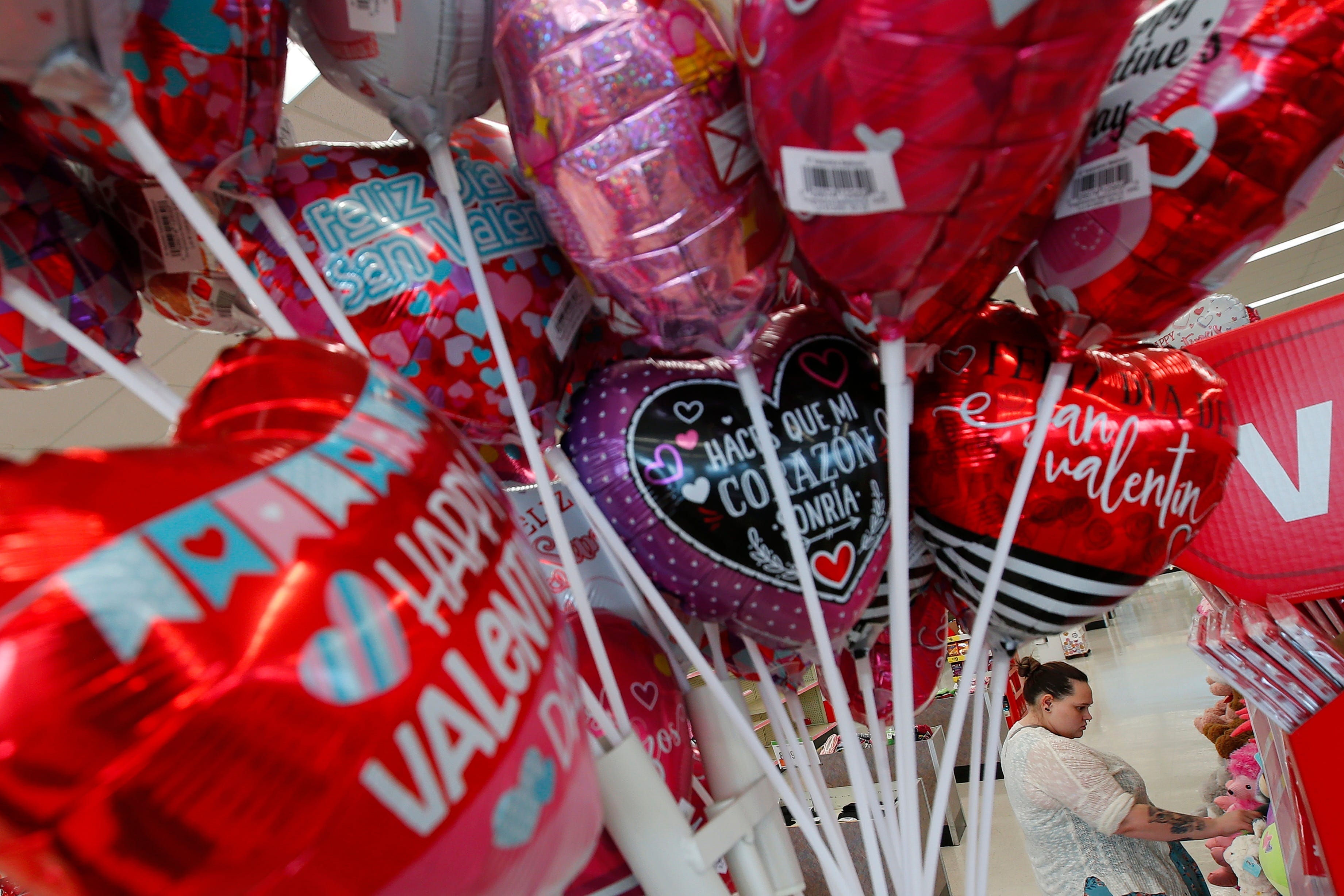 Colorful Valentine's Day balloons are seen in the foreground as a woman picks stuffed animal gifts at Walgreen's in New Bedford, Massachusetts.