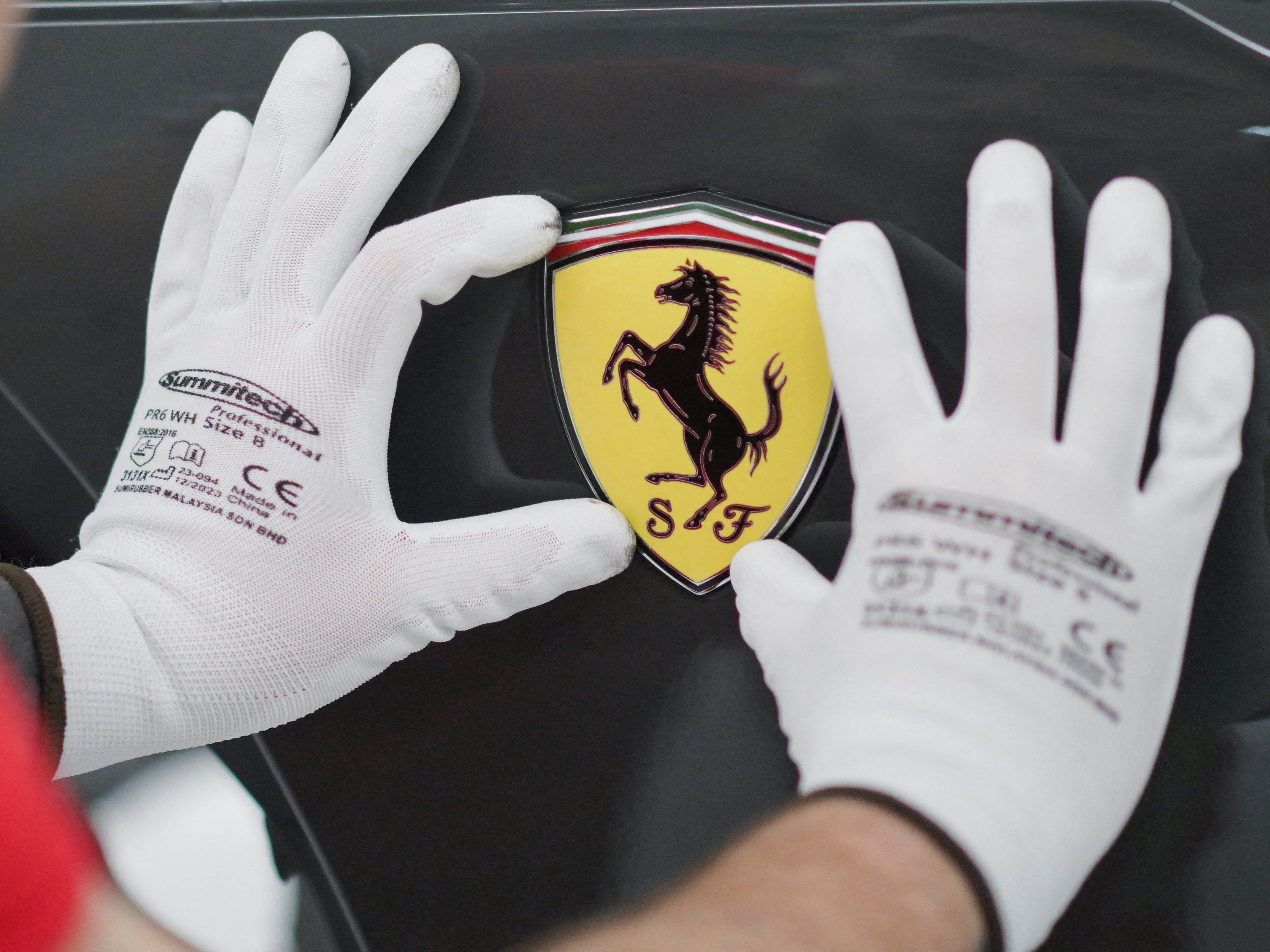 A Ferrari logo is being installed on a Ferrari car at Ferrari's new 'e-building' facility where the luxury sportscar maker is testing lines before an expected start of car production in early 2025, in Maranello, Italy, June 21, 2024.