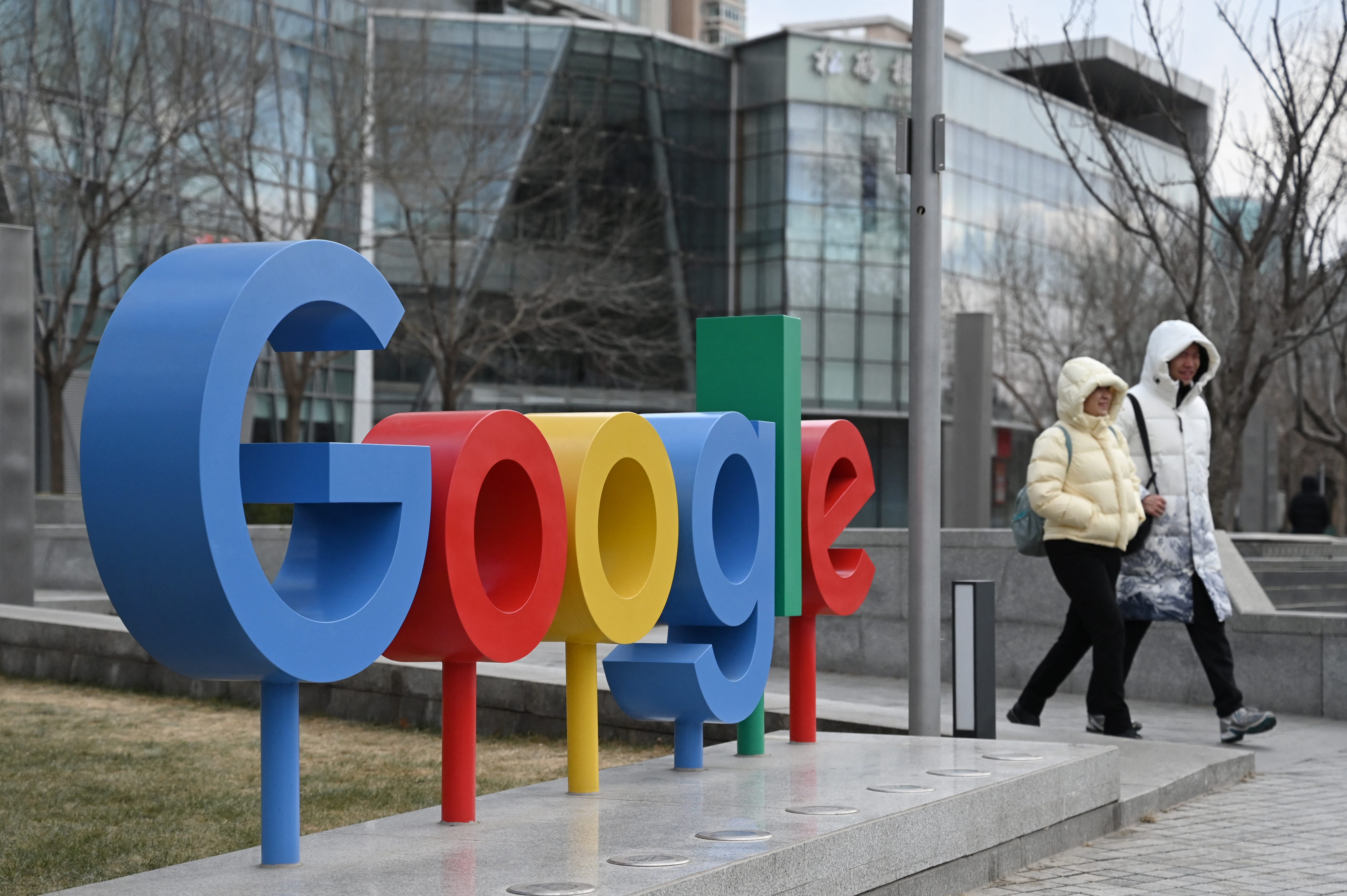 People walk past a Google logo outside a building housing Google offices in Beijing on February 4, 2025.