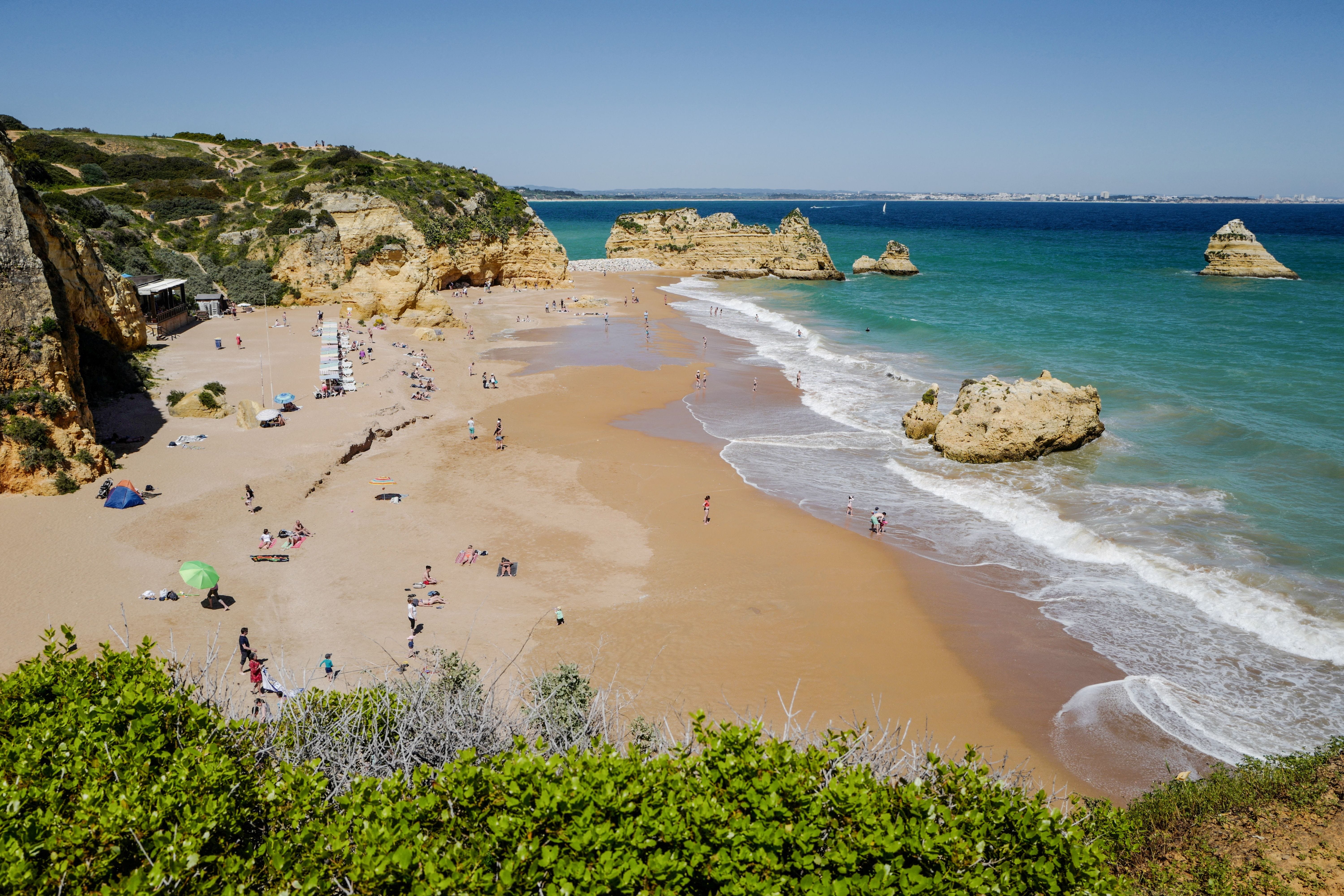 People enjoy the warm weather at the Dona Ana beach in Lagos on April 18, 2018 in the southern Portugal region of Algarve. (Photo by Ludovic MARIN / AFP) (Photo by LUDOVIC MARIN/AFP via Getty Images)