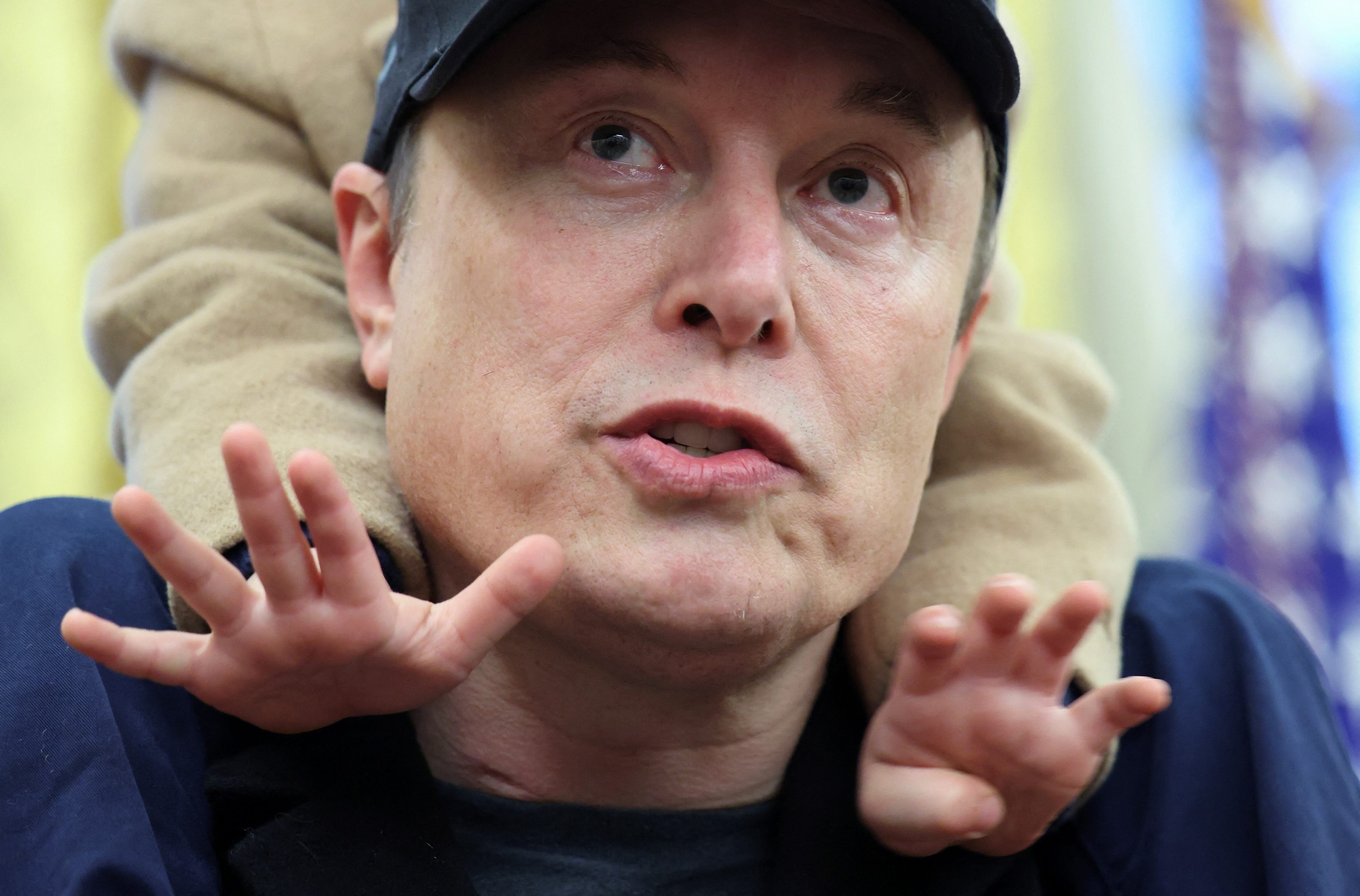 Elon Musk, with son X on his shoulders, answers reporters at a news conference in the Oval Office of the White House on Feb. 11, 2025.