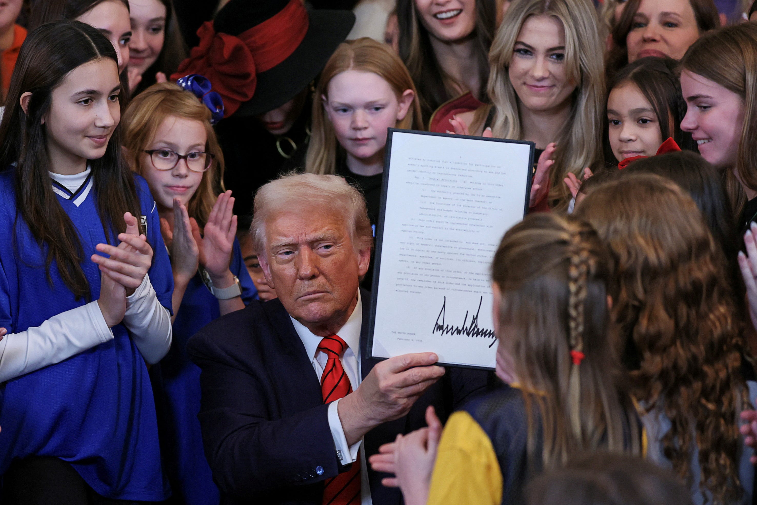 President Donald Trump holds up a signed executive order banning transgender girls and women from participating in women's sports, in the East Room at the White House in Washington, on Feb. 5, 2025.