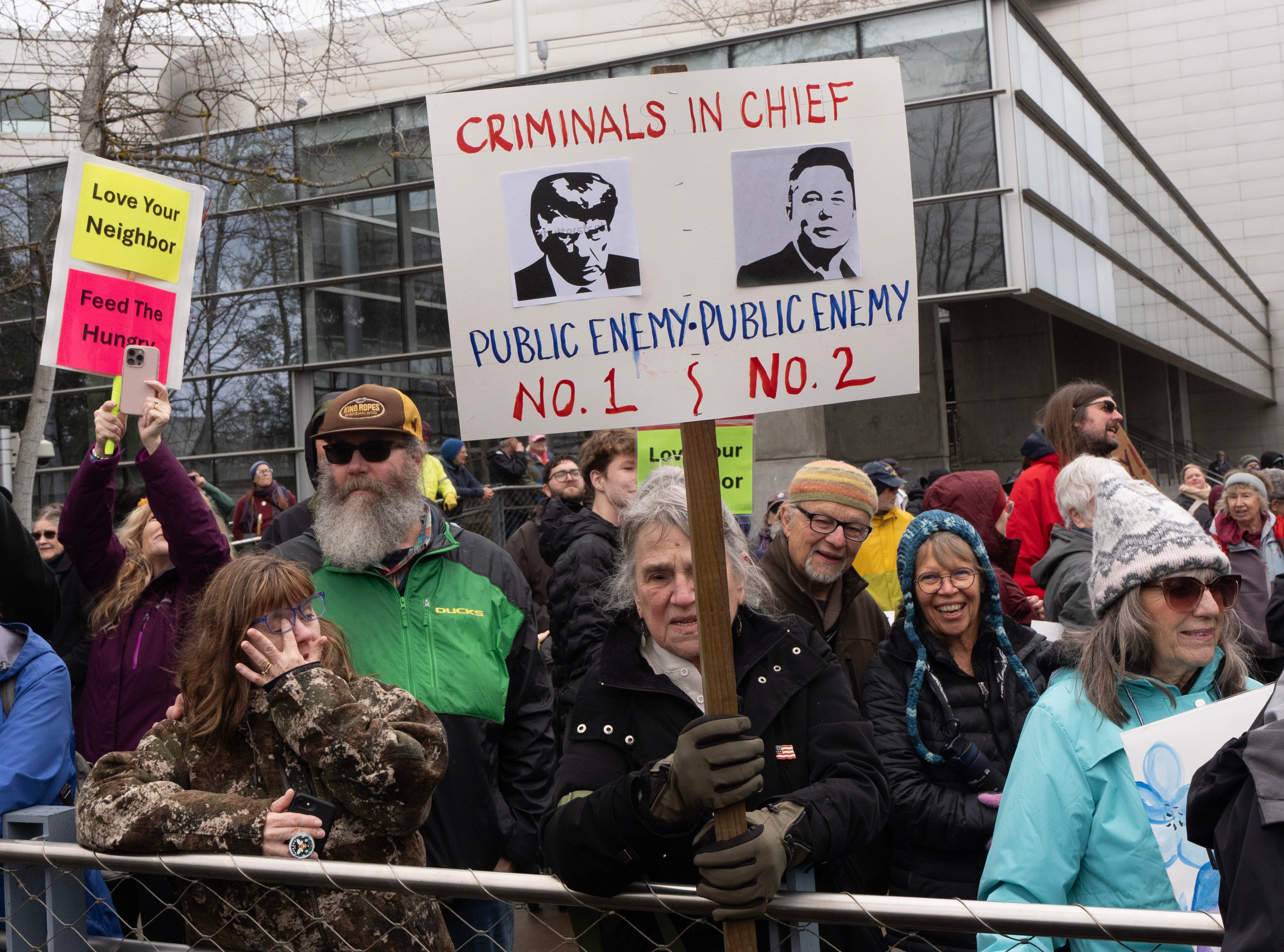 Protesters carry signs and chant in protest of actions of President Trump and Elon Musk on Presidents Day in Euguene, Oregon Monday, Feb. 17, 2025.