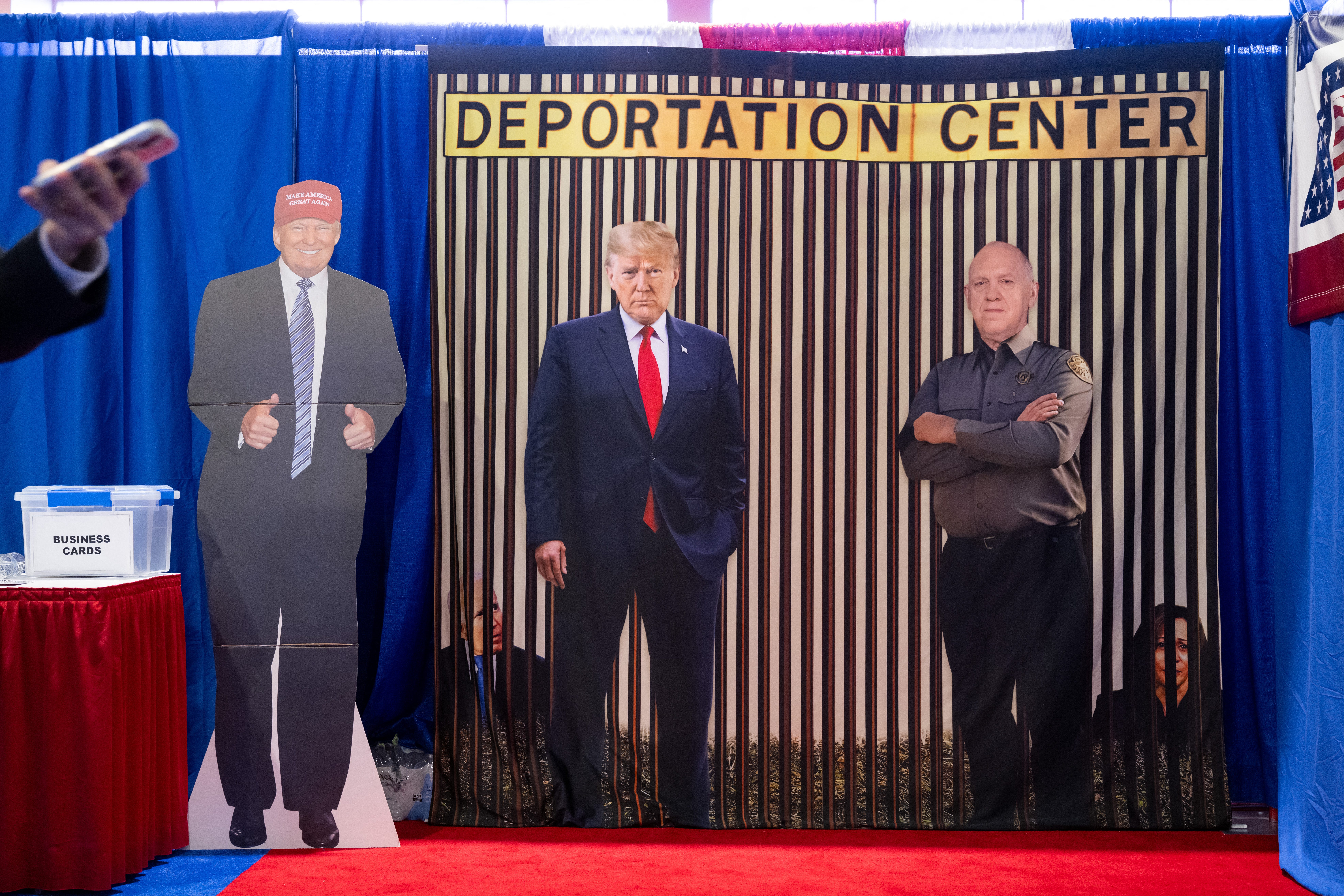Cutouts of President Donald Trump and "border czar" Tom Homan stand in front of photos of former President Joe Biden and former Vice President Kamala Harris behind bars at a "Deportation Center" vendor booth on Feb. 20, 2025, during the Conservative Political Action Conference outside Washington, D.C.