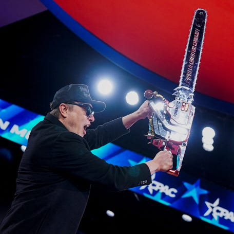 Elon Musk holds up a chainsaw onstage during the 2025 Conservative Political Action Conference (CPAC) outside Washington, DC.