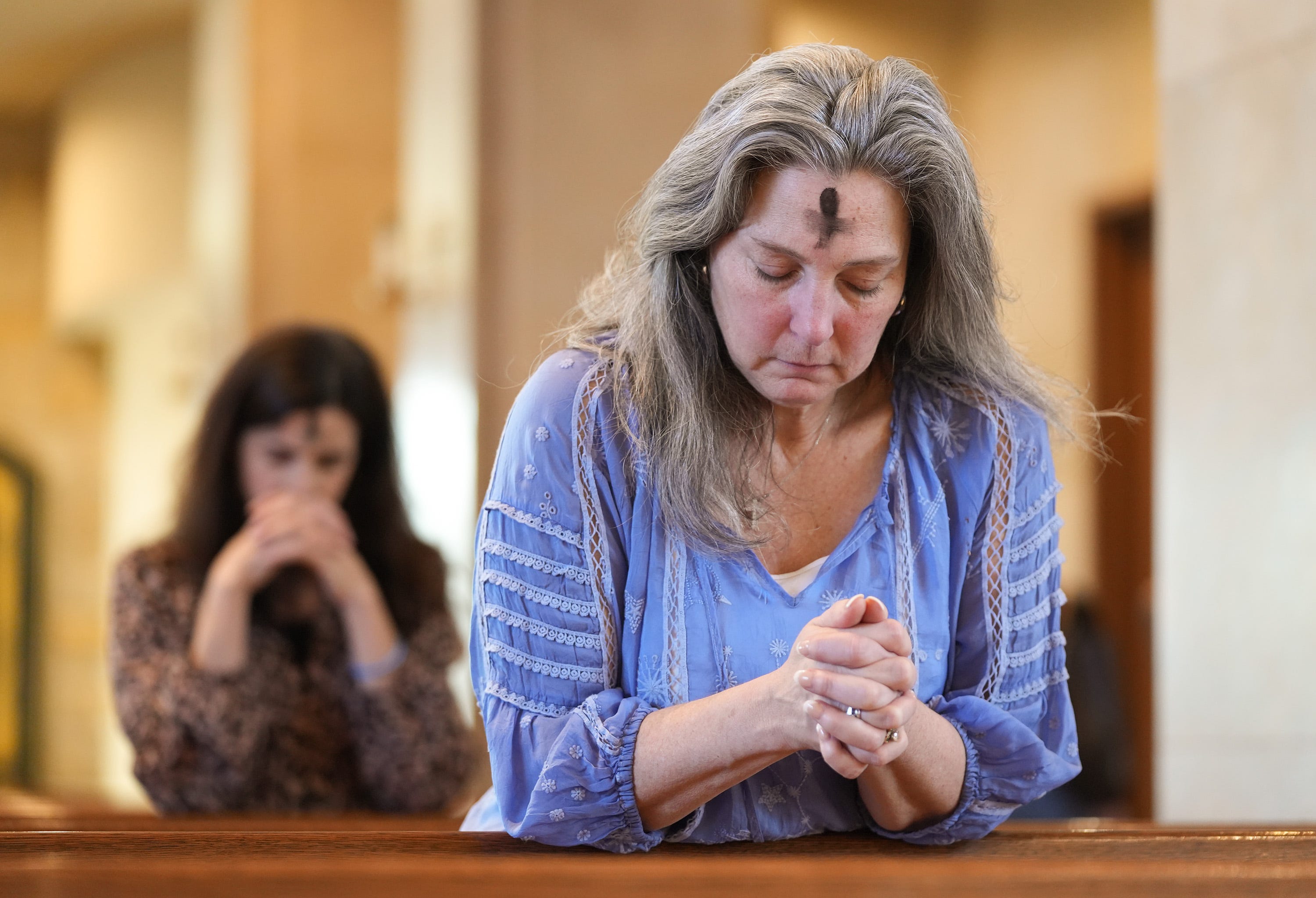 Dorsey Prince, right, and Shannon Carter pray during an Ash Wednesday Mass at St. John Neumann Catholic Church on Wednesday Feb. 22, 2023. Ash Wednesday marks the first day of Lent, a 40-day period of solemn observance that ends on Easter Sunday.