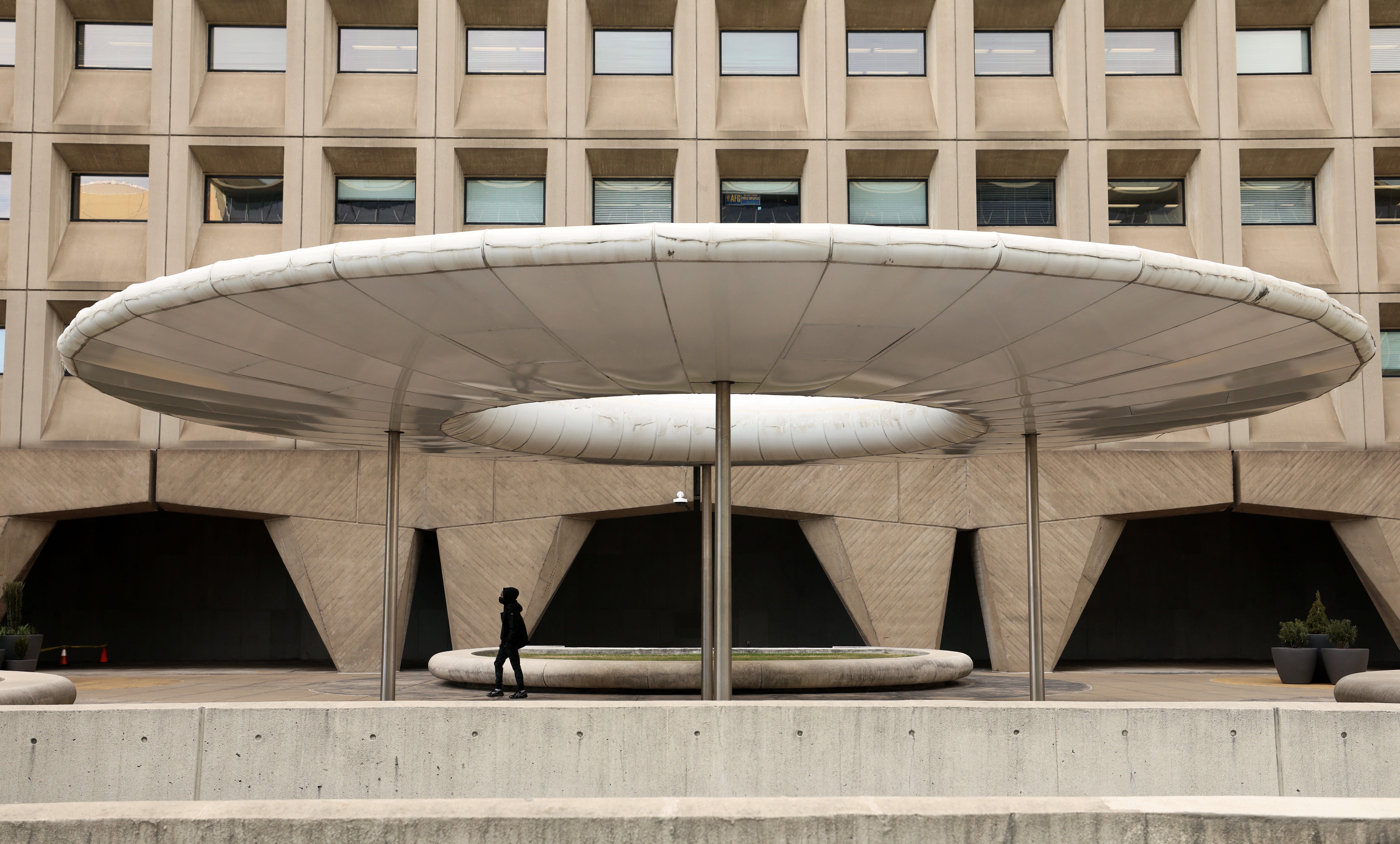 A person walks under a shade canopy in front of the headquarters of the Federal Department of Housing and Urban Development (HUD), days after President Donald Trump offered buyouts to thin the ranks of civil-service workers, in Washington, D.C.