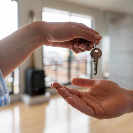 Close-up on a real estate agent giving the keys of his new house to a man - home ownership concepts