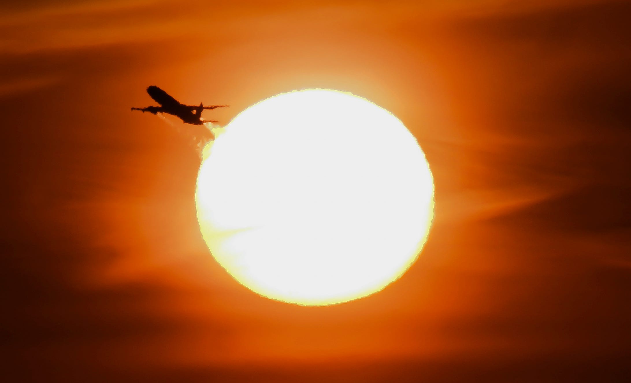The silhouette an airplane departing from Palm Springs International Airport passes in front of the sunrise on Dec. 21, 2024, one of the busiest travel days of the year.