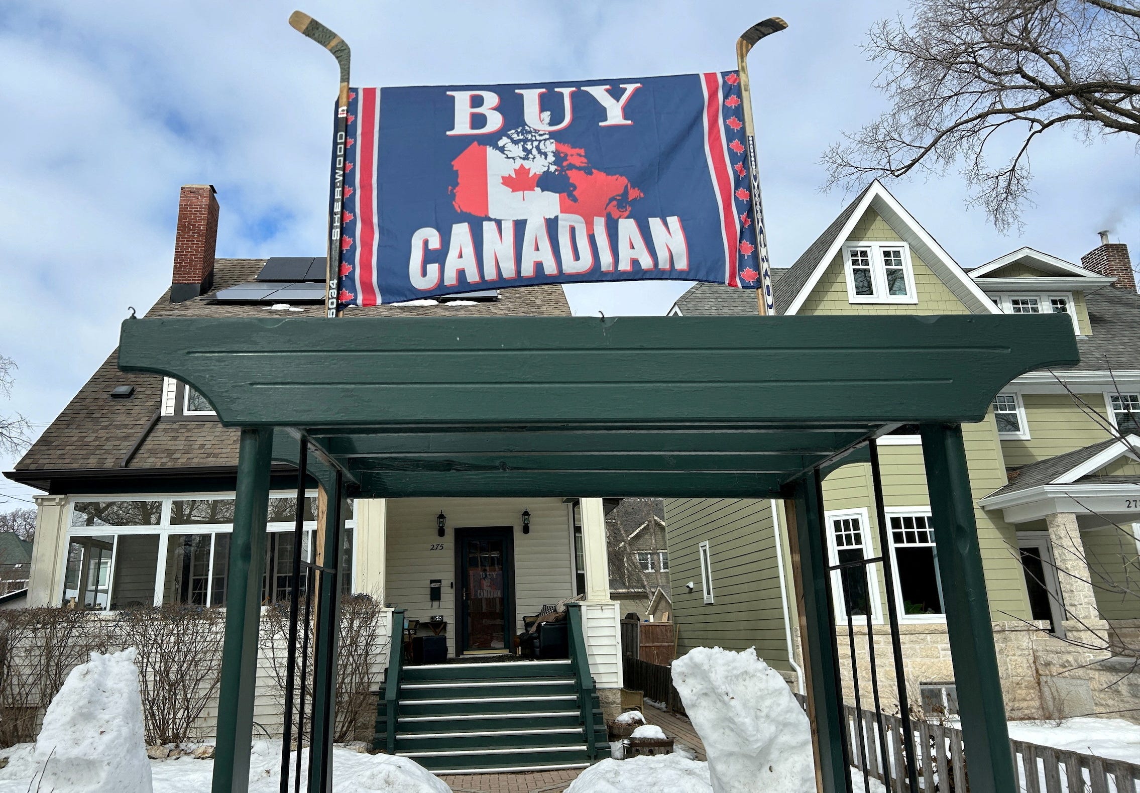 A banner reading "Buy Canadian", in response to U.S. President Donald Trump's 25% tariffs on goods from Canada, is held aloft by a pair of hockey sticks in front of a house in Winnipeg, Manitoba, Canada on March 5, 2025.