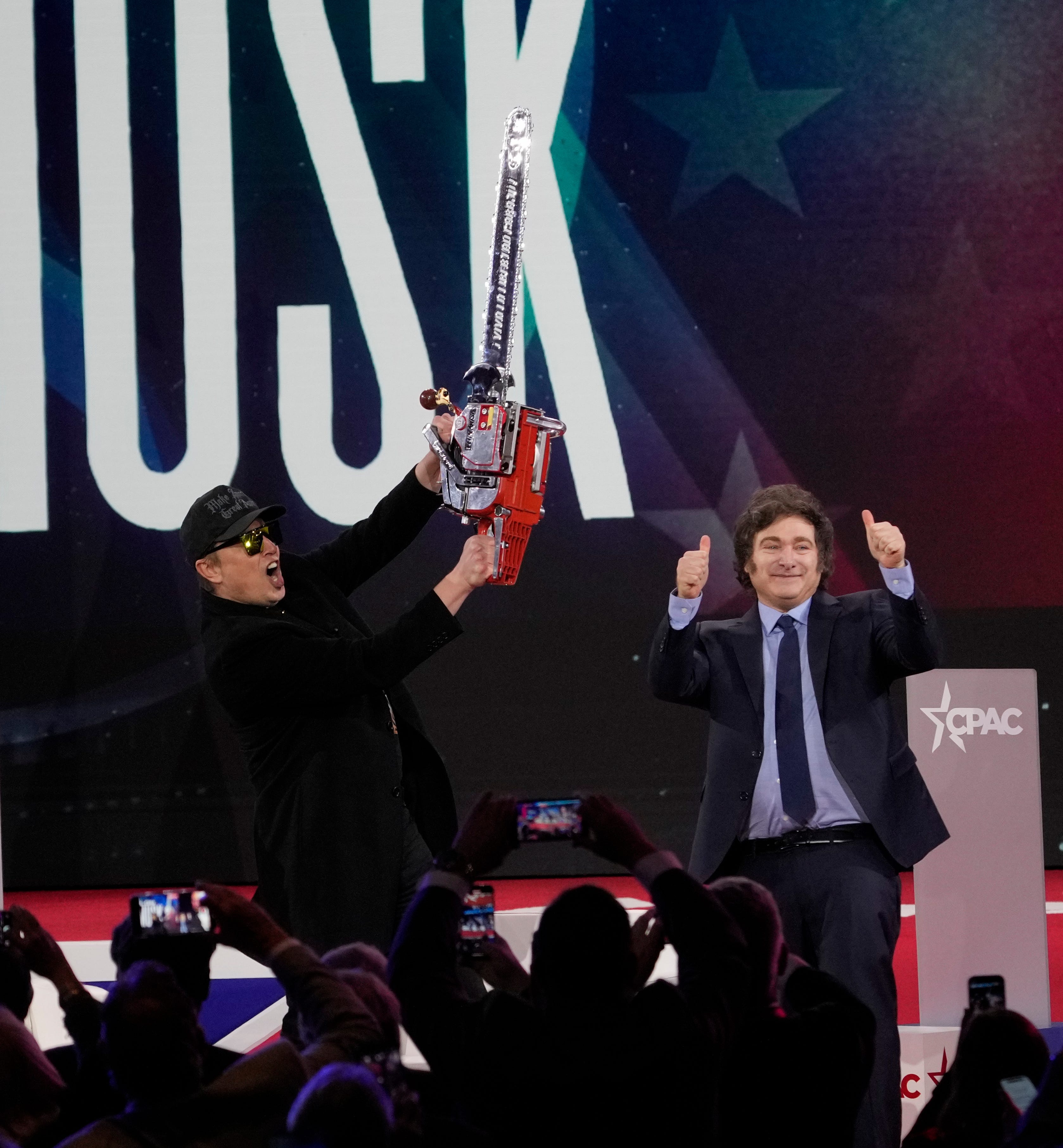 Elon Musk waving a chainsaw presented to him by Argentine President Javier Milei, right, at the Conservative Political Action Conference (CPAC) on Feb. 20, 2025.
