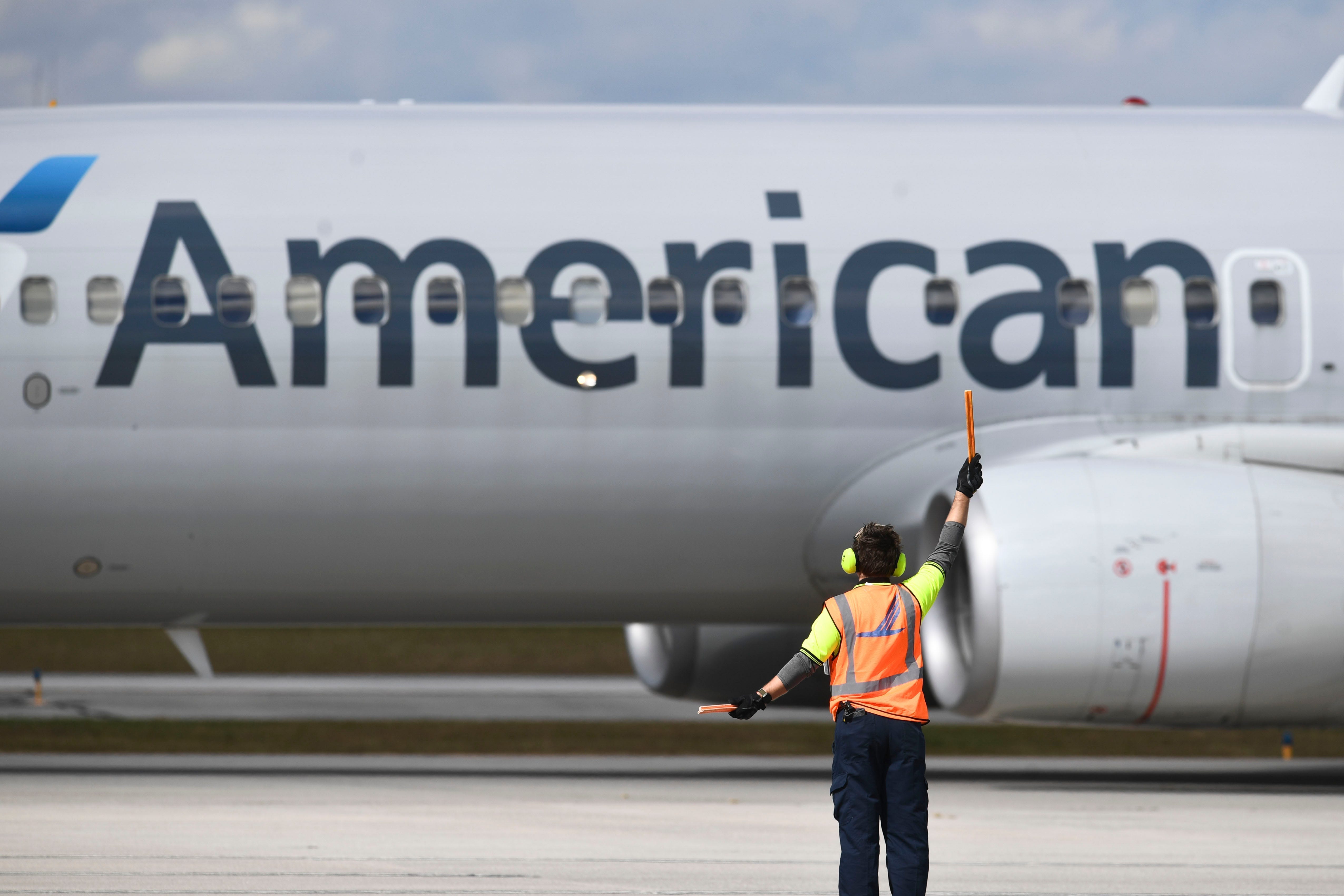 Airport ground crew is pictured directing an American Airlines plane.