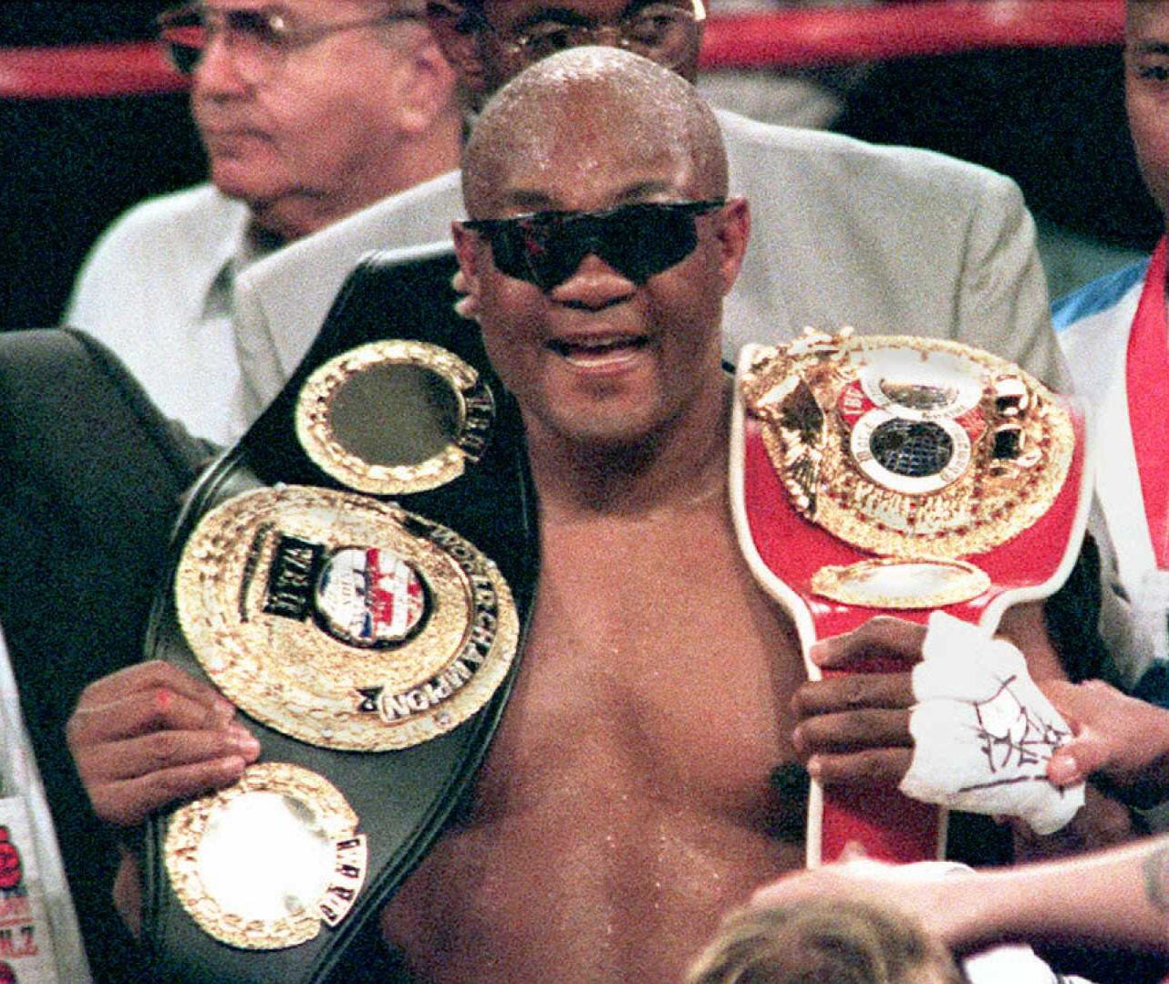 IBF heavyweight champion George Foreman smiles as he holds belts for the International Boxing Federation and World Boxing Union championship after defeating Axel Schulz in a 12-round decision at the MGM Grand Garden in Las Vegas on April 22, 1995.