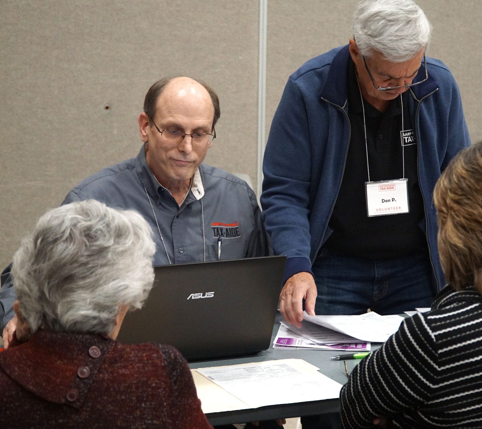 Tax Aide Jack Motz, left, helps to check the tax-filings of some visitors to AARP's free 2018 tax filing gathering on March 13 at the Novi Civic Center.            Noviciviccenterbusyday6