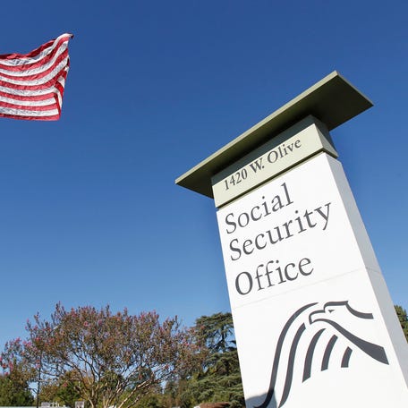 An American flag flutters in the wind next to signage for a United States Social Security Administration office in Burbank, California on October 25, 2012.