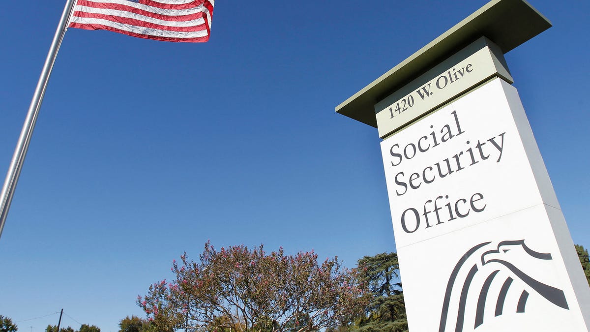 An American flag flutters in the wind next to signage for a United States Social Security Administration office in Burbank, California on October 25, 2012.