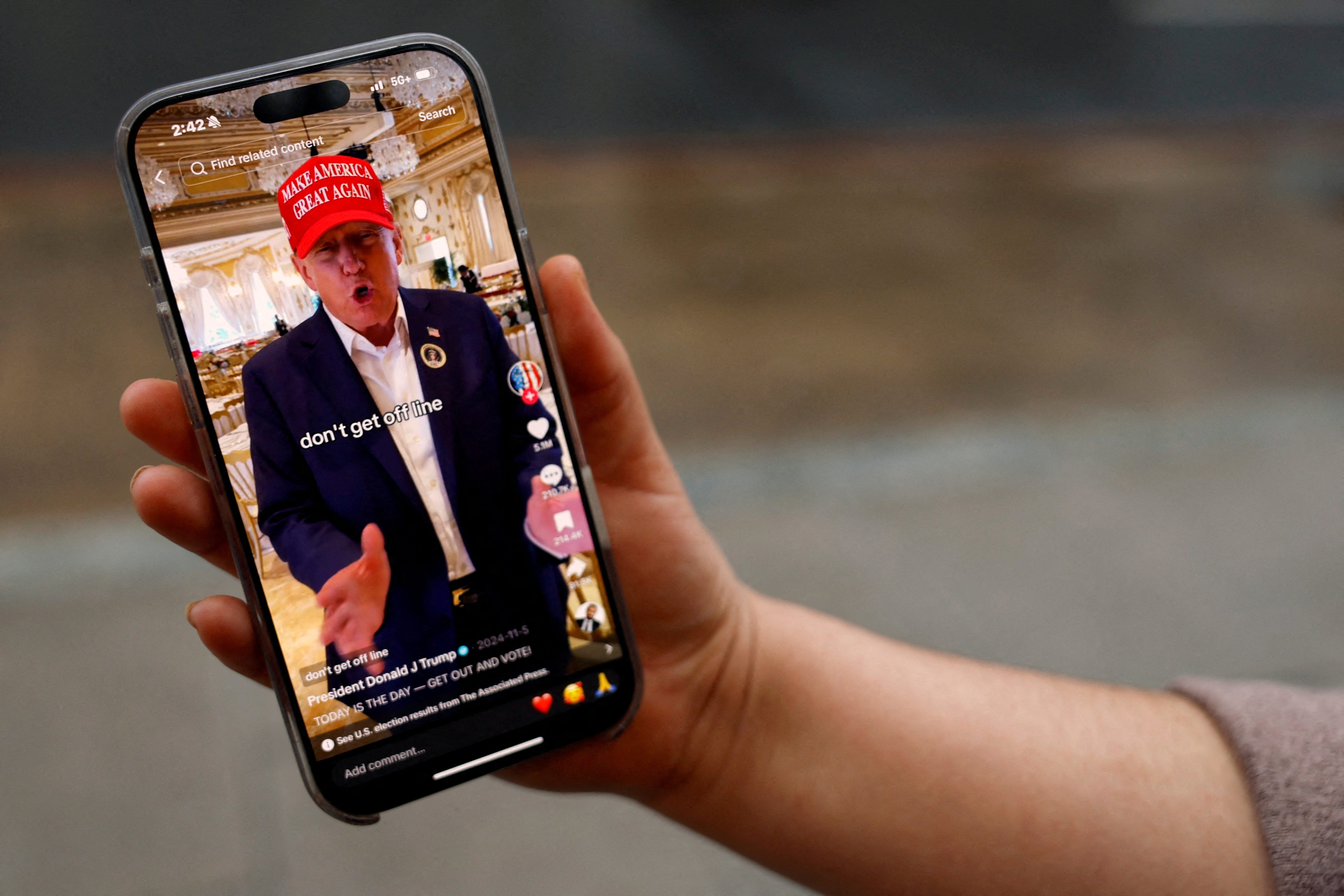 A woman poses with her smartphone displaying the @realdonaldtrump TikTok page