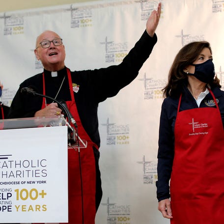 Timothy Cardinal Dolan stands with New York Governor Kathy Hochul as he blesses a gathering of people to receive free food supplies at a food distribution held by the Catholic Charities of the Archdiocese of New York ahead of the Thanksgiving holiday in the Harlem section of Manhattan in New York City, New York, U.S., Nov. 23, 2021.
