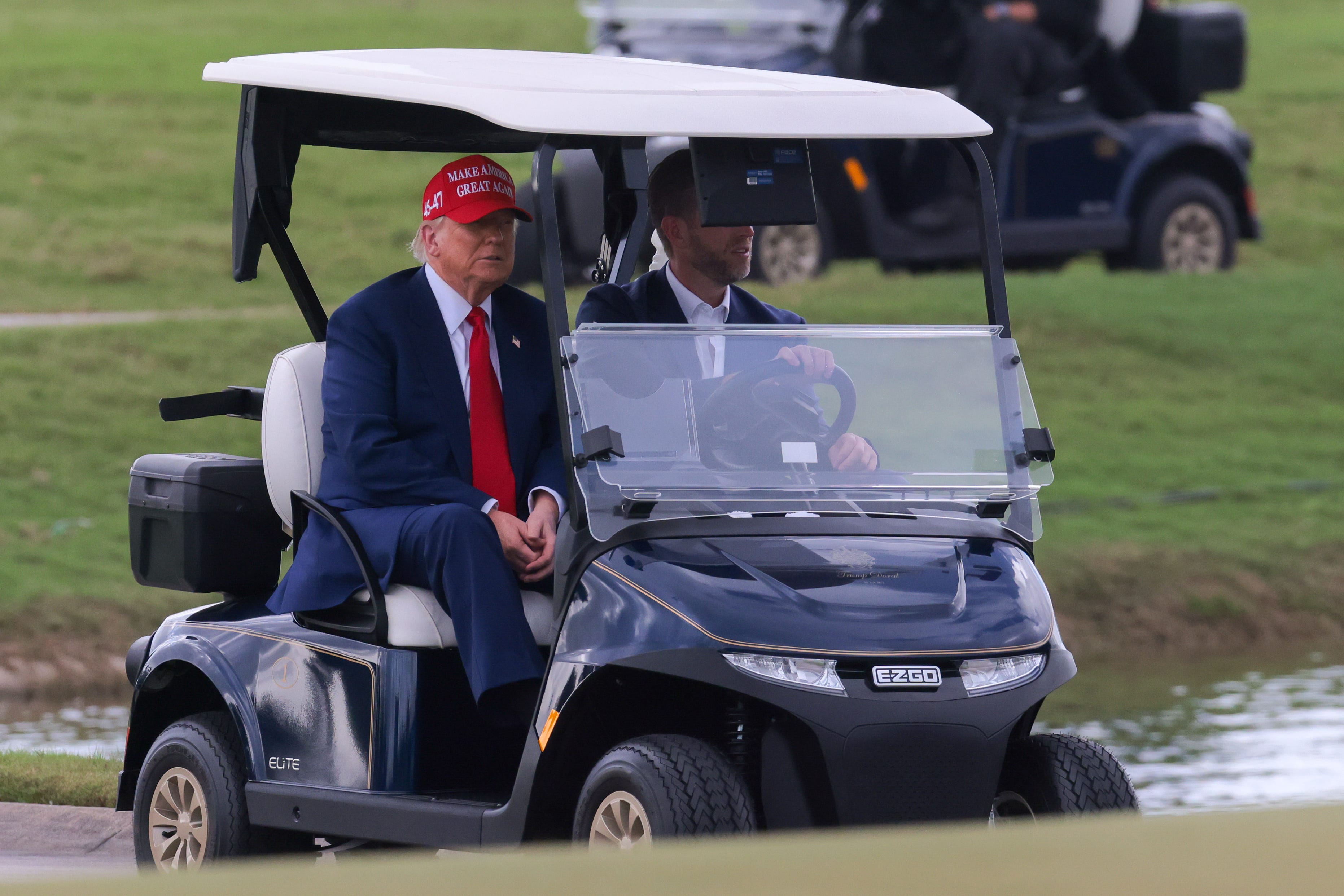 Apr 3, 2025; Miami, Florida, USA; President Donald Trump and his son, Eric Trump, drive in a golf cart after he arrived on Marine One at the LIV Golf Miami golf tournament at Trump National Doral. Mandatory Credit: Sam Navarro-Imagn Images