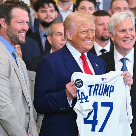 President Donald Trump holds up a jersey alongside pitcher Clayton Kershaw (L) and team owner Mark Walter (R) during an event honoring the 2024 World Series champions Los Angeles Dodgers in the East Room of the White House in Washington, DC, on April 7, 2025.