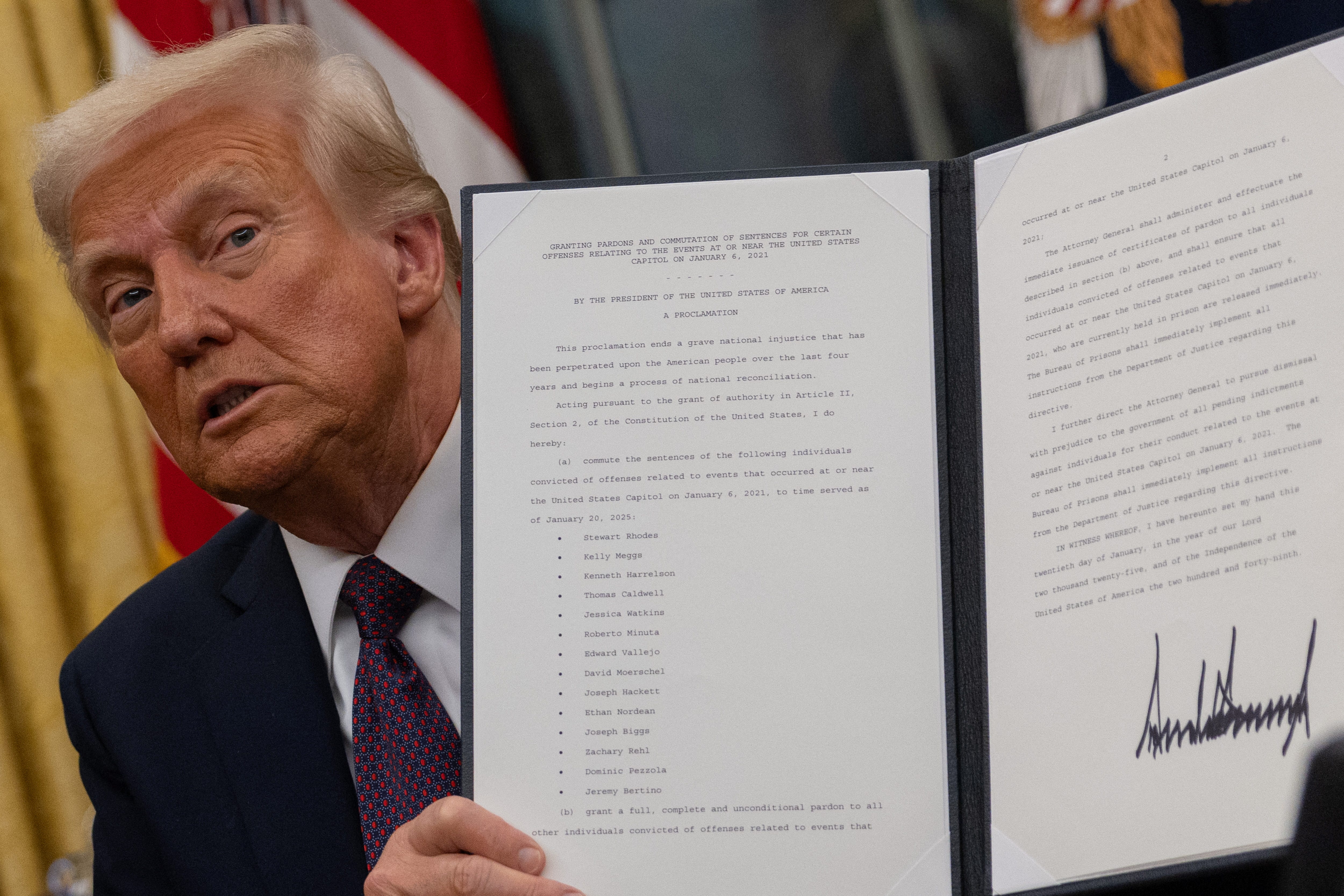 U.S. President Donald Trump looks on as he issues executive orders and pardons for Jan. 6 defendants, whose names are seen on the document he holds, in the Oval Office at the White House on Inauguration Day in Washington, U.S., January 20, 2025.