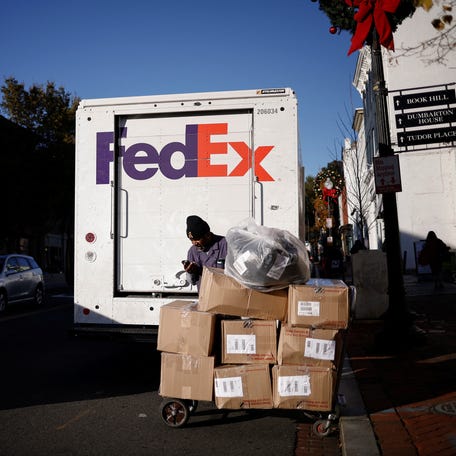 A driver of FedEx stands with packages near a delivery truck during Black Friday preparations in the Georgetown neighborhood of Washington, U.S., November 26, 2024.