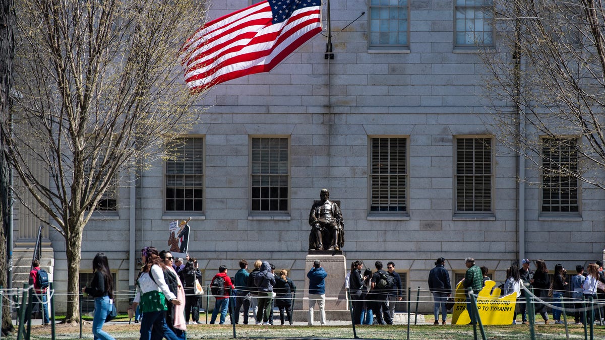 Demonstrators with signs stand around the John Harvard Statue in Harvard Yard after a rally was held against President Donald Trump's attacks on Harvard University in Cambridge, Mass., on April 17, 2025. US President Donald Trump called Harvard a "joke" on April 16, 2025, and said it should lose its government research contracts after the prestigious university refused demands that it accept outside political supervision and ordered the freezing of $2.2 billion in federal funding to Harvard this week. The Department of Homeland Security (DHS) also canceled $2.7 million worth of research grants to Harvard on Wednesday and threatened the university's ability to enroll international students unless it turns over records on visa-holders' "illegal and violent activities."