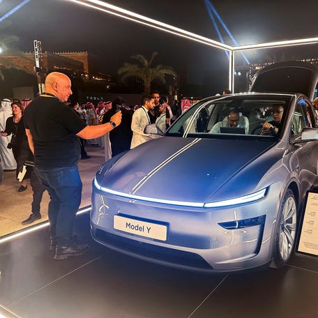 A guest takes photos of Tesla Model Y, displayed during the inauguration ceremony of the first Tesla showroom in Riyadh, Saudi Arabia. April 10, 2025.