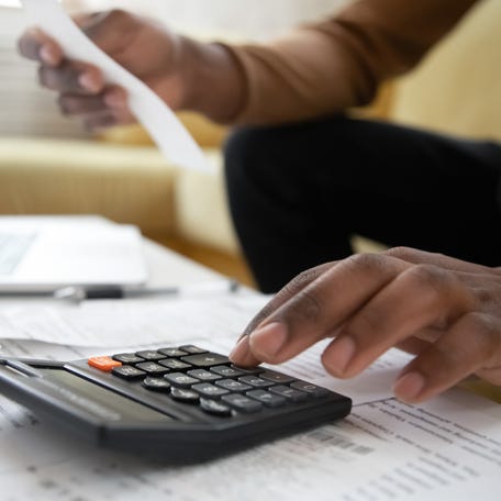 Close up of man with calculator checking bills at home.