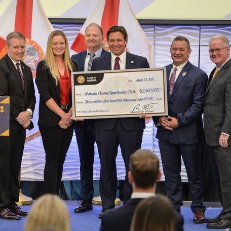 Florida Gov. Ron DeSantis presents a check at the Indian River State College in Fort Pierce on April 23, 2025.
