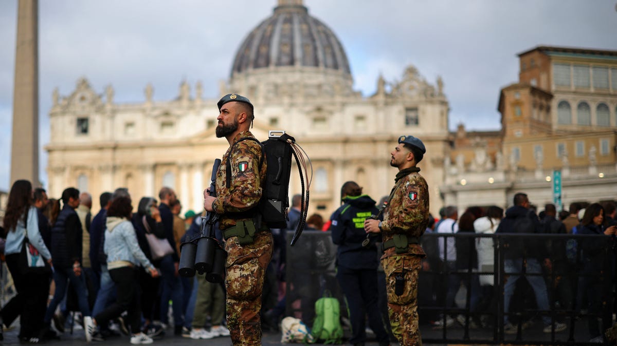 Security personnel stand guard as faithful stand in line to enter St. Peter's Basilica to pay respect as Pope Francis lies in state, in Rome, Italy on April 25, 2025.