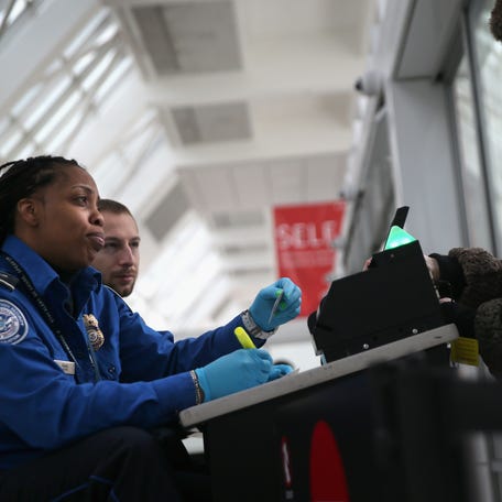 A TSA agent checks a traveler's identification at a special TSA Pre-check lane at Terminal C of the LaGuardia Airport.