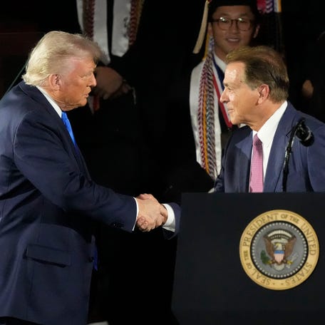 President Donald Trump shakes hands with Alabama football coach Nick Saban before speaking to Alabama graduates on Thursday.