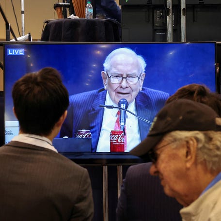 People watch as Berkshire Hathaway chairman Warren Buffett is seen on a screen speaking at the Berkshire Hathaway Inc annual shareholders' meeting, in Omaha, Nebraska, U.S., May 3, 2025.