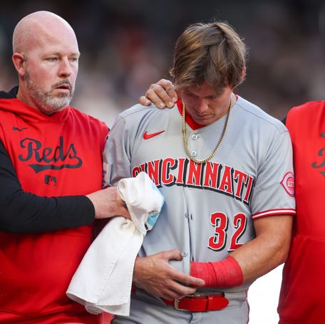 Cincinnati Reds left fielder Tyler Callihan, center, leaves Monday night's game against the Atlanta Braves with an injury in the third inning.
