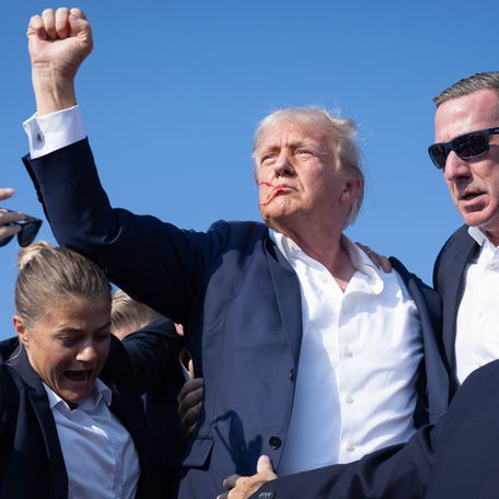 Republican presidential nominee Donald Trump defiantly pumps his fist after being shot at and rushed offstage during a reelection campaign rally on July 13, 2024, in Butler, Pennsylvania.