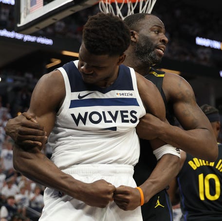 Anthony Edwards reacts as Draymond Green hangs on during Game 1 of the Warriors-Timberwolves second-round series.