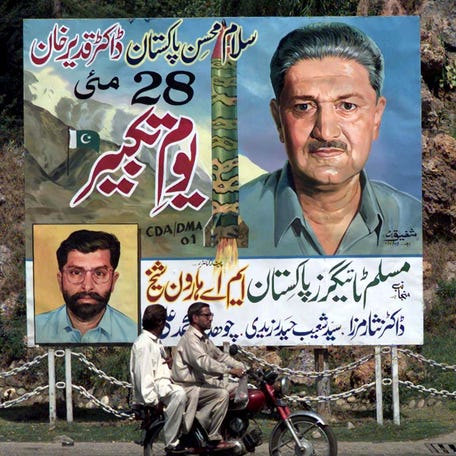 Two Pakistanis on a motor bike, pass a billboard with a portrait of Pakistani nuclear scientist A.Q. Khan and a picture of the Ghauri II surface-to-surface missile at Islamabad's main boulevard May 19, 1999.