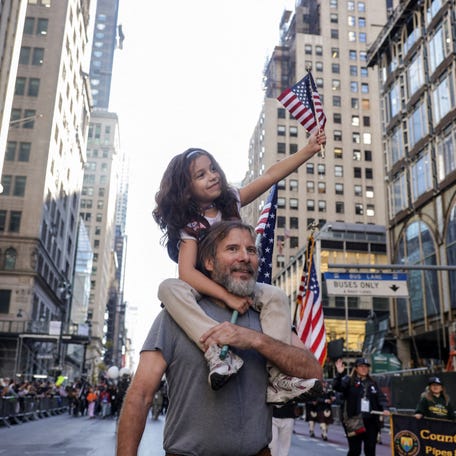 A child riding piggyback holds a U.S. flag during the annual Veteran's Day Parade in New York City, U.S., November 11, 2024.
