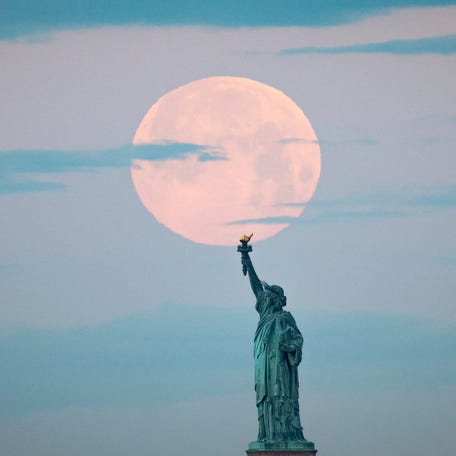 May's full Moon, known as the Full Flower Moon, sets behind the Statue of Liberty on May 7, 2020 in New York City