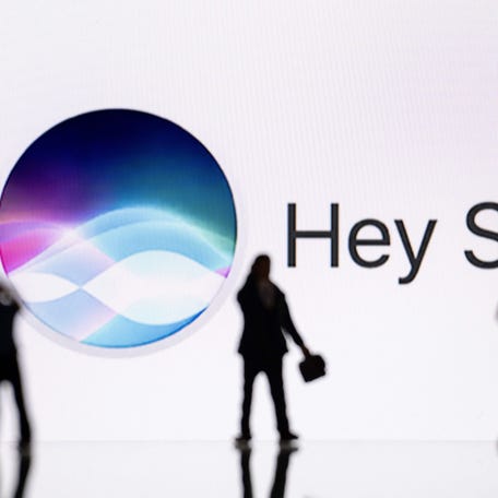 This illustration photograph taken on October 30, 2023, in Mulhouse, eastern France, shows figurines next to a screen displaying a logo of Siri, a digital assistant of Apple Inc. technology company.