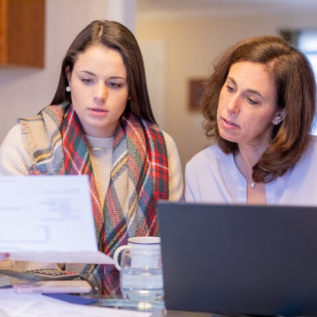 Mother and daughter at home reconciling bank statements.