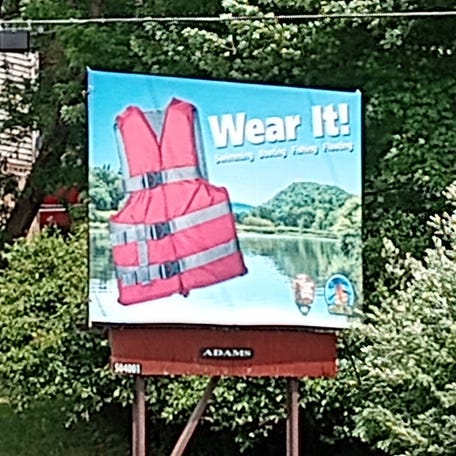 The National Park Service at the Upper Delaware Scenic & Recreational River has put up new billboards urging river users to wear life jackets. This sign is posted along New York Route 97 opposite from the Roebling Bridge and Lackawaxen, Pennsylvania.