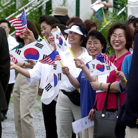Members of the Korean Society of Montgomery wave flags and welcome dignitaries to the groundbreaking ceremony of the Hyundai plant near Montgomery on Tuesday April 16, 2002.    Mickey Welsh / Staff