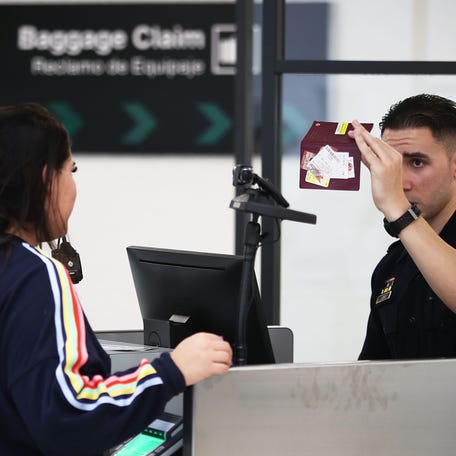 A U.S. Customs and Border Protection officer checking someone's passport in Miami.