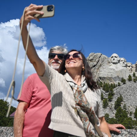 A couple takes a selfie with the national monument in the background on Friday, May 9, 2025, at Mount Rushmore National Memorial in Keystone, South Dakota.